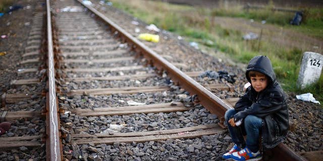 A young boy rests on the railway track near a temporary holding center for migrants near the border between Serbia and Hungary in Roszke, southern Hungary in Roszke, Saturday, Sept. 12, 2015. Leaders of the United Nations refugee agency warned Tuesday that Hungary faces a bigger wave of 42,000 asylum seekers in the next 10 days and will need international help to provide shelter on its border. (AP Photo/Matthias Schrader)