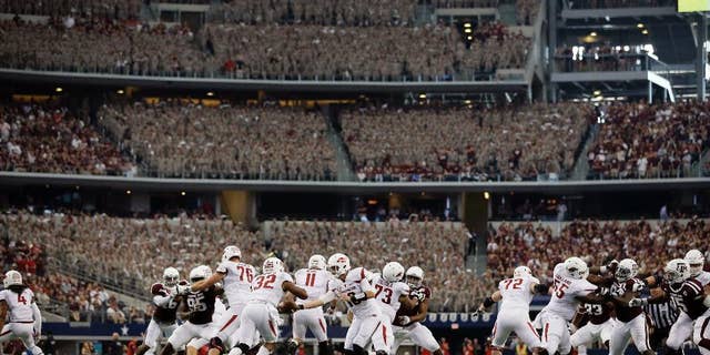 Arkansas quarterback Brandon Allen (10) hands off to running back Jonathan Williams (32) in the first half of an NCAA college football game against Texas A&M, Saturday, Sept. 27, 2014, in Arlington, Texas. The Aggie Corps. of Cadets fill the stadium seats at rear during the game. (AP Photo/Tony Gutierrez)
