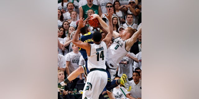 Michigan State's Russell Byrd (0) blocks a shot by Michigan's Glenn Robinson III as Michigan State's Gary Harris (14) defends during the second half of an NCAA college basketball game, Saturday, Jan. 25, 2014, in East Lansing, Mich. Michigan won 80-75. (AP Photo/Al Goldis)