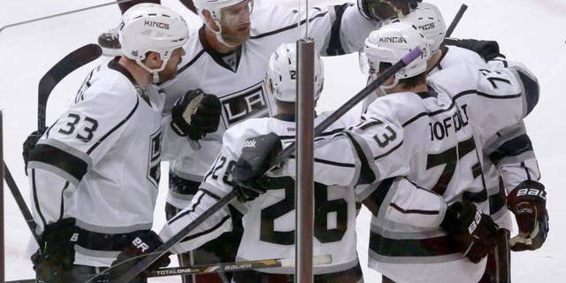 The Los Angeles Kings gather around center Tyler Toffoli as they celebrate Toffoli's goal during the third period of Game 2 of the Western Conference finals in the NHL hockey Stanley Cup playoffs against the Chicago Blackhawks on Wednesday, May 21, 2014, in Chicago. From left are Willie Mitchell (33), Jeff Carter (77), Slava Voynov (26), Toffoli, and Tanner Pearson. (AP Photo/Charles Rex Arbogast)