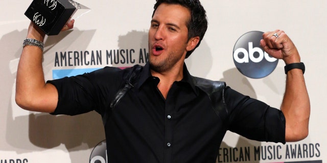 November 24, 2013. Luke Bryan poses with his award for favorite country male artist at the 41st American Music Awards in Los Angeles, California.