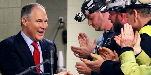 FILE - In this April 13, 2017 file photo Environmental Protection Agency (EPA) Administrator Scott Pruitt, left, shakes hands with coal miners during a visit to Consol Pennsylvania Coal Company's Harvey Mine in Sycamore, Pa. The Trump administration wants to trash Obama-era rules to limit water pollution from coal-fired power plants. Pruitt announced the change this week. Administrator Scott Pruitt sent a letter to a coalition of energy companies that lobbied against the 2015 water pollution rule. (AP Photo/Gene J. Puskar, File)