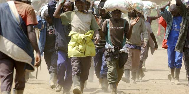 Men carry bags of cassiterite, coltan and computers, and manganese on May 28, 2013 from the Mudere mine, near Rubaya, some 9 kms from the eastern Democratic Republic of Congo city of Goma.