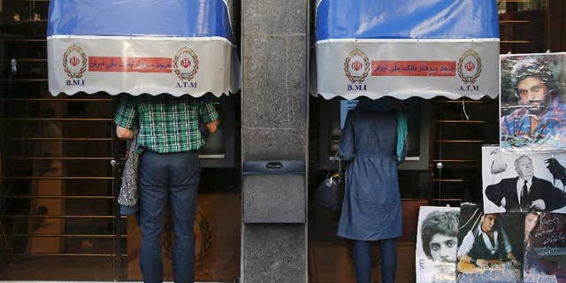 FILE -- In this April 4, 2015 file photo, Iranians use ATM machines of Bank Melli Iran in downtown Tehran, Iran. Iranian media are saying the country's banks will begin issuing credit cards for the first time in decades. Reports by several newspapers, including the daily Donya-e-Eqtesad, Monday, Sept. 26, 2016 said the cards will be for domestic use only and do not involve any sort of partnership with a major international credit card company. So far, Iranian banks have only issued debit and prepaid cards. (AP Photo/Vahid Salemi, File)