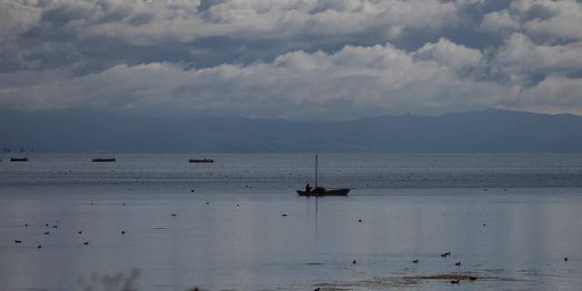 FILE - In this May 24, 2011, file photo, a man rows a boat in lake Titicaca, in Desaguadero, Bolivia. The lake is about to get a major clean up after years of uncontrolled pollution, as Peruvian President Pedro Pablo Kuczynski announced the construction of 10 treatment plants on rivers emptying into Lake Titicaca. He made the announcement Friday, Jan 13, 2017 during a visit to the high-altitude lake straddling the border with Bolivia. (AP Photo/Juan Karita, File)