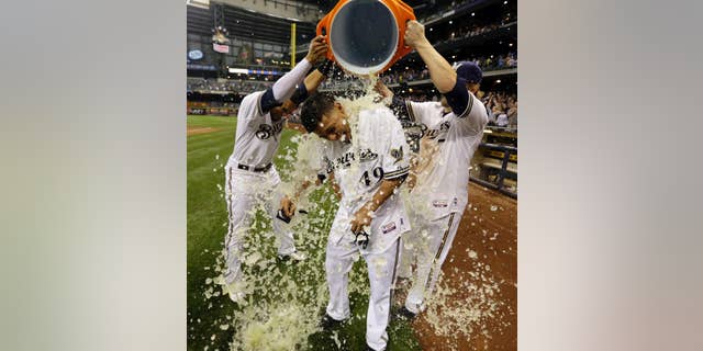 Milwaukee Brewers' Yovani Gallardo is dunked by teammates Mark Reynolds (7) and Carlos Gomez after hitting a game-winning double during the 10th inning of a baseball game against the Baltimore Orioles Tuesday, May 27, 2014, in Milwaukee. The Brewers won 7-6. (AP Photo/Morry Gash)