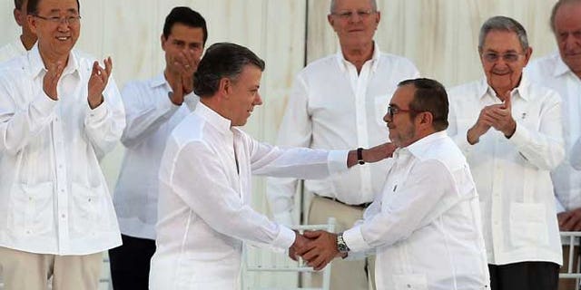 Colombia’s President Juan Manuel Santos, front left, and the top commander of the Revolutionary Armed Forces of Colombia (FARC) Rodrigo Londono, known by the alias Timochenko, shake hands after signing the peace agreement between Colombia’s government and the FARC to end over 50 years of conflict in Cartagena, Colombia, Monday, Sept. 26, 2016. Behind, from left, are U.N. Secretary General Ban Ki Moon, Mexico's President Enrique Pena Nieto, Peru's President Pedro Pablo Kuczynski, Cuba's President Raul Castro, and Spain's former King Juan Carlos. (AP Photo/Fernando Vergara)