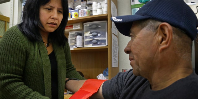Laura Lopez, left, checks the blood pressure of Santos Aguilar Wednesday, Jan. 23, 2013, at the Street Level Health Project in Oakland, Calif. (AP Photo/Ben Margot)