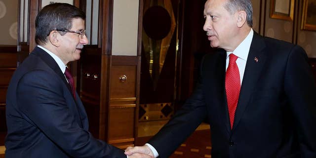 Turkey's President Recep Tayyip Erdogan, right, shakes hands with Prime Minister Ahmet Davutoglu before a meeting in Ankara, Turkey, Tuesday, Aug. 25, 2015. Erdogan on Tuesday appointed Davutoglu to form an interim government that will lead the country into a new election, likely to take place on Nov. 1. Erdogan formally called for a new election late on Monday, following an inconclusive vote in June, and the collapse of coalition-building efforts.(Presidential Press Service via AP, Pool)