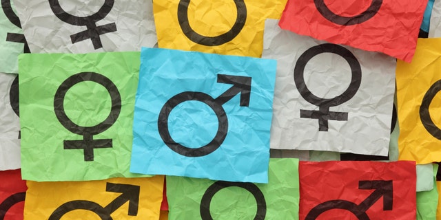 Crumpled colorful paper notes with gender symbols.