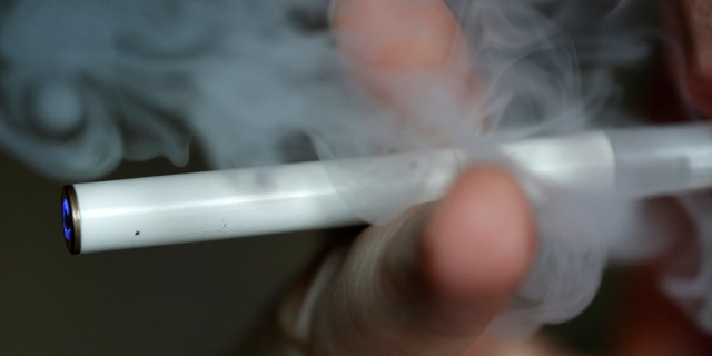 A man uses an E-cigarette, an electronic substitute in the form of a rod, slightly longer than a normal cigarette, in this illustration picture taken in Paris, March 5, 2013. A changeable filter contains a liquid with nicotine and propylene glycol. When the user inhales as he would when smoking, air flow is detected by a sensor and a micro-processor activates an atomizer which injects tiny droplets of the liquid into the flowing air, producing a vapour. The E cigarette is powered by a rechargeable battery. REUTERS/Christian Hartmann (FRANCE - Tags: HEALTH SOCIETY SCIENCE TECHNOLOGY) - RTR3ELVI