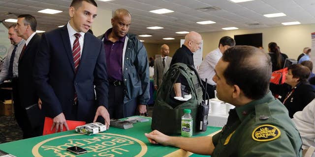 In this photo taken Friday, Feb. 6, 2015, U.S. Marine Corps Veteran Christopher Triana,left, talks about job probabilities to U.S. Border Patrol agent Frank Miller, right, at the annual Veterans Career and Resource Fair in Miami. The U.S. Labor Department reports on the number of people who applied for unemployment benefits for the week ending Feb. 21 on Thursday, Feb. 26, 2015. (AP Photo/Alan Diaz)