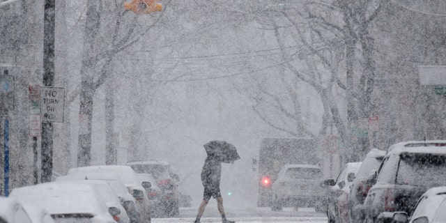 A man is shown crossing the street during a snowstorm in Hoboken, N.J., in March 2018 in this photo. This year's winter solstice — the shortest day in the Northern Hemisphere — begins on Dec. 21, 2021. From there, the days will gradually grow longer.