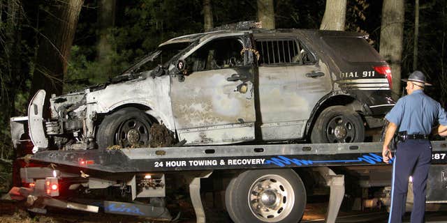 Sept. 2, 2015: A police officer watches as a cruiser that was shot at is removed from Forest Road