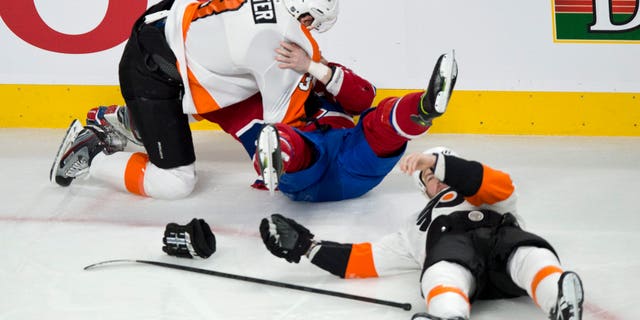 Philadelphia Flyers' Kurtis Foster charges Montreal Canadiens' Ryan White as Flyers' Kent Huskins lies on the ice after taking a hit from White during the first period of an NHL hockey game on Monday, April 15, 2013 in Montreal. (AP Photo/The Canadian Press, Paul Chiasson)