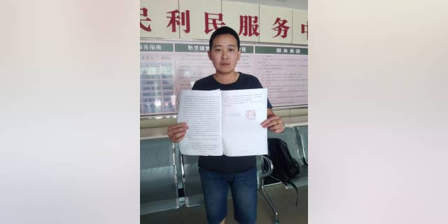 In this photo released by Mr. C, a transgender man who uses the name Mr. C to protect his parents from discrimination, holds up the arbitration results while posing for a photo at a government office in Guiyang in southwestern China's Guizhou province Tuesday, May 10, 2016. Mr. C said he was disappointed but will continue to fight for equality after a labor arbitration panel on Tuesday, rejected his complaint that he was fired unfairly, in China's first transgender job discrimination case. (Mr. C via AP)