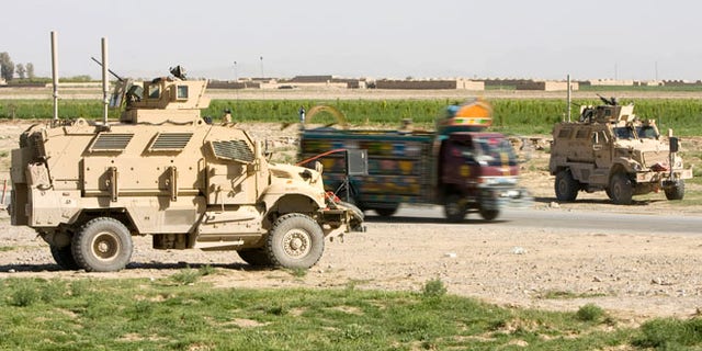 March 25, 2010: An Afghan truck is driven past U.S. Army Mine Resistant Ambush Protected (MRAP) armored vehicles of 508th Special Troops Battalion, 82nd Airborne Division, at an Afghan Police checkpoint on the Highway One, the main Afghan road around the country, outside the town of Kandahar, southern Afghanistan.  Police and sheriff's departments in the U.S. have obtained 165 MRAP vehciles leftover from the Iraq war.