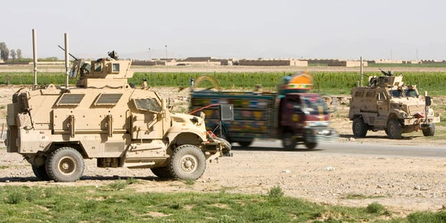 March 25, 2010: An Afghan truck is driven past U.S. Army Mine Resistant Ambush Protected (MRAP) armored vehicles of 508th Special Troops Battalion, 82nd Airborne Division, at an Afghan Police checkpoint on the Highway One, the main Afghan road around the country, outside the town of Kandahar, southern Afghanistan. Police and sheriff's departments in the U.S. have obtained 165 MRAP vehciles leftover from the Iraq war.