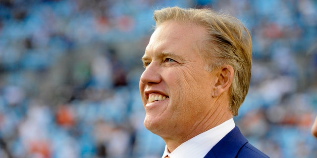 FILE - This is a Nov. 11, 2012 file photo showing Denver Broncos executive vice president, John Elway, watching players warm up prior to an NFL football game between the Carolina Panthers and the Denver Broncos in Charlotte, N.C. Elway could very well be directing his greatest comeback from a leather chair in an office. (AP Photo/Mike McCarn, File)