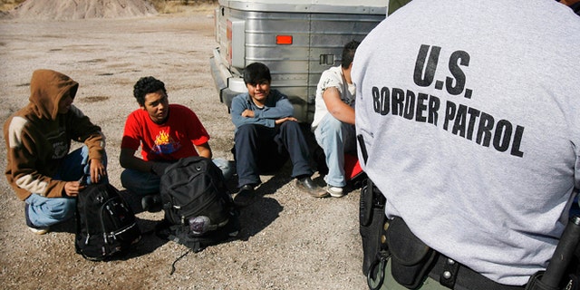 FILE - In this Jan. 19, 2007 file photo, the U.S. Border Patrol detains a large group of suspected immigrants at the Arizona-Mexico border in Sasabe, Ariz. A federal judge has barred use of a policy that allowed people who paid to be sneaked into the United States to be charged under Arizonaâs immigrant smuggling law as conspirators to the crime. U.S. District Judge Robert Broomfieldâs ruling said the interpretation of the 2005 state law conflicts with federal law. The ruling is the latest in a series of restrictions placed on Maricopa County Sheriff Joe Arpaioâs immigration enforcement efforts. (AP Photo/Ross D. Franklin, File)