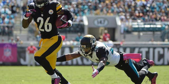 Pittsburgh Steelers running back Le'Veon Bell (26) breaks away from Jacksonville Jaguars strong safety Josh Evans, right, for yardage during the first half of an NFL football game in Jacksonville, Fla., Sunday, Oct. 5, 2014. (AP Photo/Phelan M. Ebenhack)