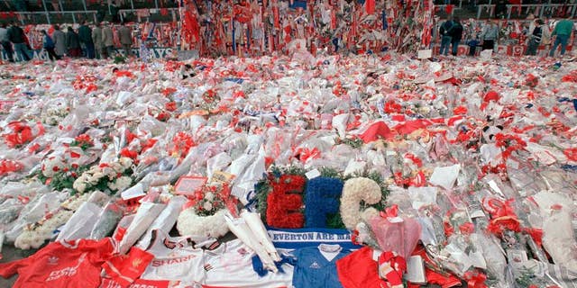 FILE- In this file photo dated April 17, 1989, floral tributes are placed by soccer fans at the 'Kop' end of Anfield Stadium in Liverpool, England, on April 17, 1989, after the Hillsborough April 15 tragedy when fans surged forward during the Cup semi-final between Liverpool and Nottingham Forest at Hillsborough Stadium killing 96 people. The 96 Liverpool soccer fans who died in the Hillsborough Stadium disaster were “unlawfully killed” because of errors by the police, a jury concluded Tuesday April 26, 2016. (AP Photo/ Peter Kemp, File)