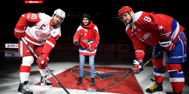 Fatima Al Ali takes part in ceremonial puck drop Thursday with Alex Ovechkin (8) of the Washington Caps and Henrik Zetterberg of the Detroit Red Wings.