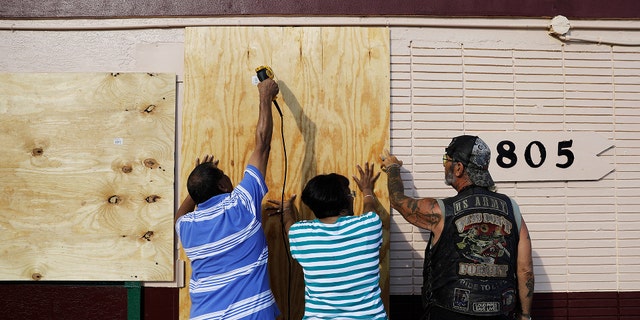 Richard Jay, left, and his wife Shanta get help from their tenant Anthony Perreria, right, as they board up their motel ahead of Hurricane Irma in Daytona Beach, Fla., Friday, Sept. 8, 2017. Coastal residents around South Florida have been ordered to evacuate as the killer storm closes in on the peninsula for what could be a catastrophic blow this weekend. (AP Photo/David Goldman)