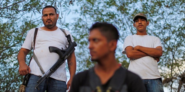 In this Nov. 5 photo, armed men from to a self-defense group create a checkpoint in the town of Las Colonias, Mexico. Several communities have created their own self-defense groups after a pseudo-religious cartel, known as the "Knights Templar," has for years demanded protection payments from cattlemen, lime growers and other businesses. The groups say they are free of the cartel in several municipalities of the Tierra Caliente, or “Hot Land,” which earned its moniker for the scorching weather but whose name has also come to signify criminal activity. (AP Photo/Dario Lopez-Mills)