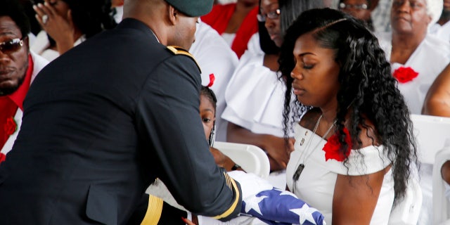 Myeshia Johnson, wife of U.S. Army Sergeant La David Johnson, receives the flag which draped his coffin at a graveside service in Hollywood, Florida