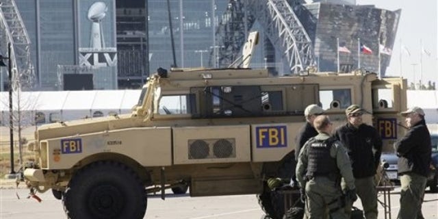 Cowboys Stadium is seen at rear as members of the FBI stand by one of their assault vehicles during a media day event where public safety agencies, local, state and federal, showed some of the equipment and tools being used to protect the public for the upcoming Super Bowl XLV NFL football game, Friday, Jan. 21, 2011, in Arlington, Texas. (AP)