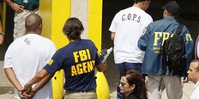 In this Oct. 6, 2010 file photo, FBI agents escort police officers and prison guards arrested in a major anti-corruption operation across the U.S. Caribbean territory to the Puerto Rico Federal Court Building in San Juan.