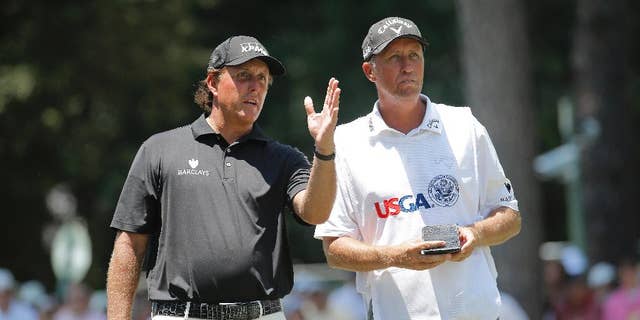 Phil Mickelson talks with his caddy on the third hole during the final round of the U.S. Open golf tournament in Pinehurst, N.C., Sunday, June 15, 2014. (AP Photo/Matt York)