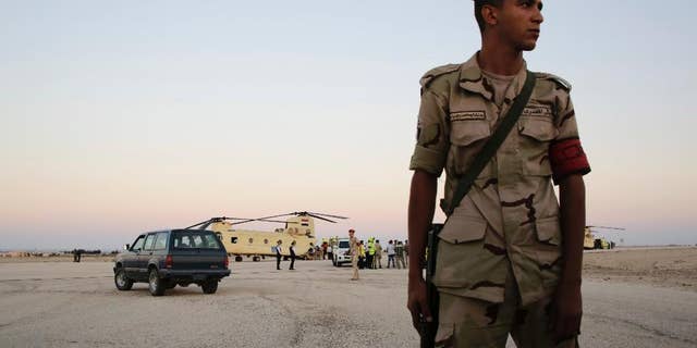 FILE - In this Saturday, Oct. 31, 2015 file photo, an Egyptian soldier stands guard as emergency workers unload bodies of victims from the crash of a Russian aircraft over the Sinai peninsula from a police helicopter to ambulances at Kabrit military airport, some 20 miles north of Suez, Egypt. Egyptians in the restive northern Sinai city of al-Arish are threatening civil disobedience to protest against what they claim to be the extrajudicial killing of six youths by security forces. (AP Photo/Amr Nabil, File)