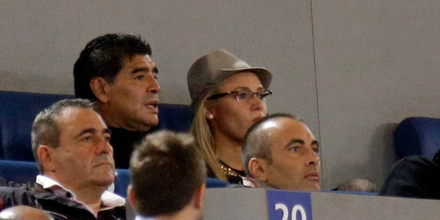 Argentine's former soccer star Diego Armando Maradona, top left, follows a Serie A soccer match between AS Roma and Napoli at Rome's Olympic stadium, Friday, Oct. 18, 2013. Italy's tax collection agency says it has formally notified Diego Maradona that it will begin procedures to freeze his assets in Italy to pay off his tax debt of $53 million. Equitalia confirmed news reports Friday saying its agents had served Maradona with the notification in his Milan hotel room, and that he signed the documentation. (AP Photo/Gregorio Borgia)