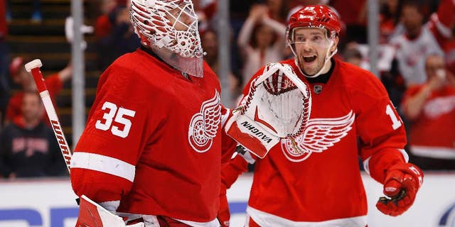 Detroit Red Wings goalie Jimmy Howard (35) celebrates with Detroit Red Wings center Pavel Datsyuk after beating the Carolina Hurricanes 3-2 in an NHL hockey game in Detroit Tuesday, April 7, 2015. (AP Photo/Paul Sancya)