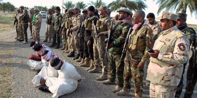 FILE - In this file photo taken Thursday, May 28, 2015, Iraq's Badr Brigades Shiite militia detain four men that they suspect of being militants of the Islamic State group outside the oil refinery in Beiji, some 155 miles (250 kilometers) north of Baghdad, Iraq. Iraqi troops backed by Shiite militias recaptured key parts of the northern refinery town of Beiji from Islamic State militants on Sunday, June 7, a general said. (AP Photo, File)