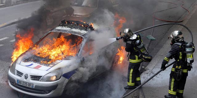 May 18, 2016: Firefighters work on a police car set up on fire by counter demonstrators while police forces gather to denounce the almost daily violent clashes at protests against a labor reform in Paris.
