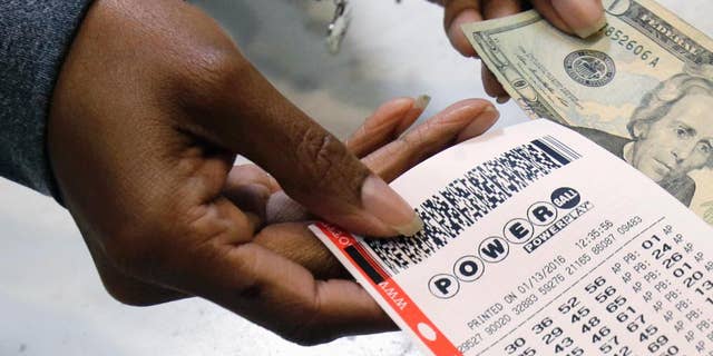FILE - In this Jan. 13, 2016 file photo, a clerk hands over a Powerball ticket for cash at Tower City Lottery Stop in Cleveland. Powerball estimates that its jackpot for the May 4, 2016, drawing is $348 million. (AP Photo/Tony Dejak, File)