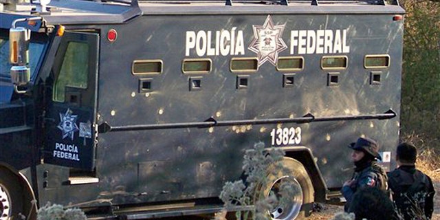 Dec. 10: Federal police agents stand next to a truck riddled with bullets in Apatzingan, Mexico.
