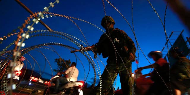 May 20, 2014: A Thai soldier mans a checkpoint as motorcyclists ride past near the site where pro-government demonstrators stage a rally on the outskirts of Bangkok, Thailand.