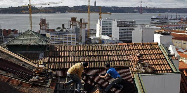 FILE - In this Feb. 28, 2014 file photo, construction workers repair the roof of a building in Lisbon. The country’s construction sector collapsed amid the financial crisis, which saw the state take a 78 billion-euro ($87 billion) bailout in 2011. The number of construction workers has more than halved from 612,000 in 2005 to roughly 277,000. (AP Photo/Francisco Seco)
