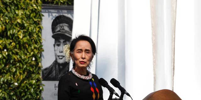 Myanmar State Counsellor Aung San Suu Kyi, standing by a portrait of her late father and national hero Gen. Aung San and the Panglong monument, delivers a speech in Feb., 2017. (AP Photo/Thein Zaw)