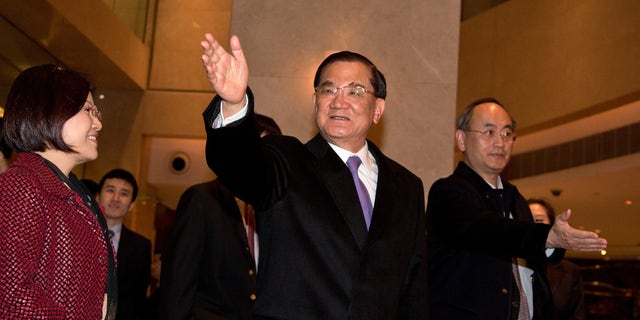 Taiwan's former vice president Lien Chan, center, waves to journalists upon arrival at a hotel in Beijing Sunday, Feb. 24, 2013. Lien Chan leads a business and politician delegation  to Beijing for a three day visit and will meet with Chinese President Hu Jintao and Communist Party Secretary General and the country's new leader Xi Jinping. (AP Photo/Andy Wong)
