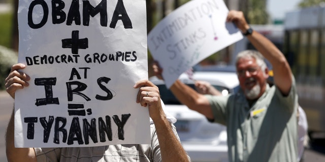 Several dozen tea party activists and other concerned citizens, wave signs and small American flags as they march outside the main Internal Revenue Service office on Tuesday, May 21, 2013, in Phoenix. The rally was one of many around the country after IRS officials acknowledged that some conservative groups received inappropriate attention and questioning. (AP Photo/Ross D. Franklin)