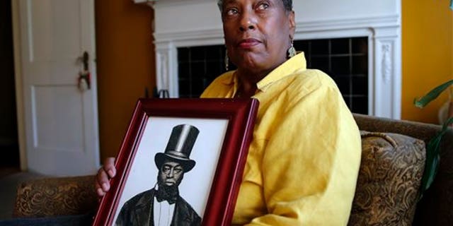 Ocea Thomas poses for a portrait with a picture of her ancestor Samuel Burris.