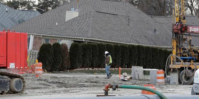 FILE - In this Jan. 4, 2017 file photo, a construction worker walks by a home collapsed by a sinkhole in Fraser, Mich.  Repairs to a broken sewer line that caused a massive sinkhole north of Detroit are estimated at more than $78 million.  (AP Photo/Carlos Osorio)