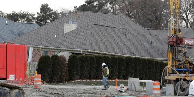FILE - In this Jan. 4, 2017 file photo, a construction worker walks by a home collapsed by a sinkhole in Fraser, Mich. Repairs to a broken sewer line that caused a massive sinkhole north of Detroit are estimated at more than $78 million. (AP Photo/Carlos Osorio)