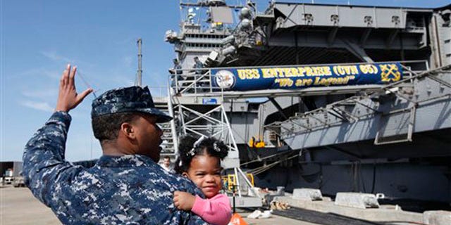 March 8, 2012: In this photo, Petty Officer 3rd Class Michael Joseph, carries his daughter Maleah, 1, to his re-enlistment ceremony aboard the nuclear powered aircraft carrier USS Enterprise at the Norfolk Naval Station in Norfolk, Va.