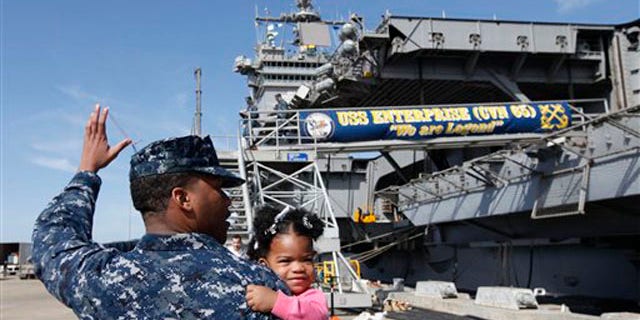 March 8, 2012: In this photo, Petty Officer 3rd Class Michael Joseph, carries his daughter Maleah, 1, to his re-enlistment ceremony aboard the nuclear powered aircraft carrier USS Enterprise at the Norfolk Naval Station in Norfolk, Va.